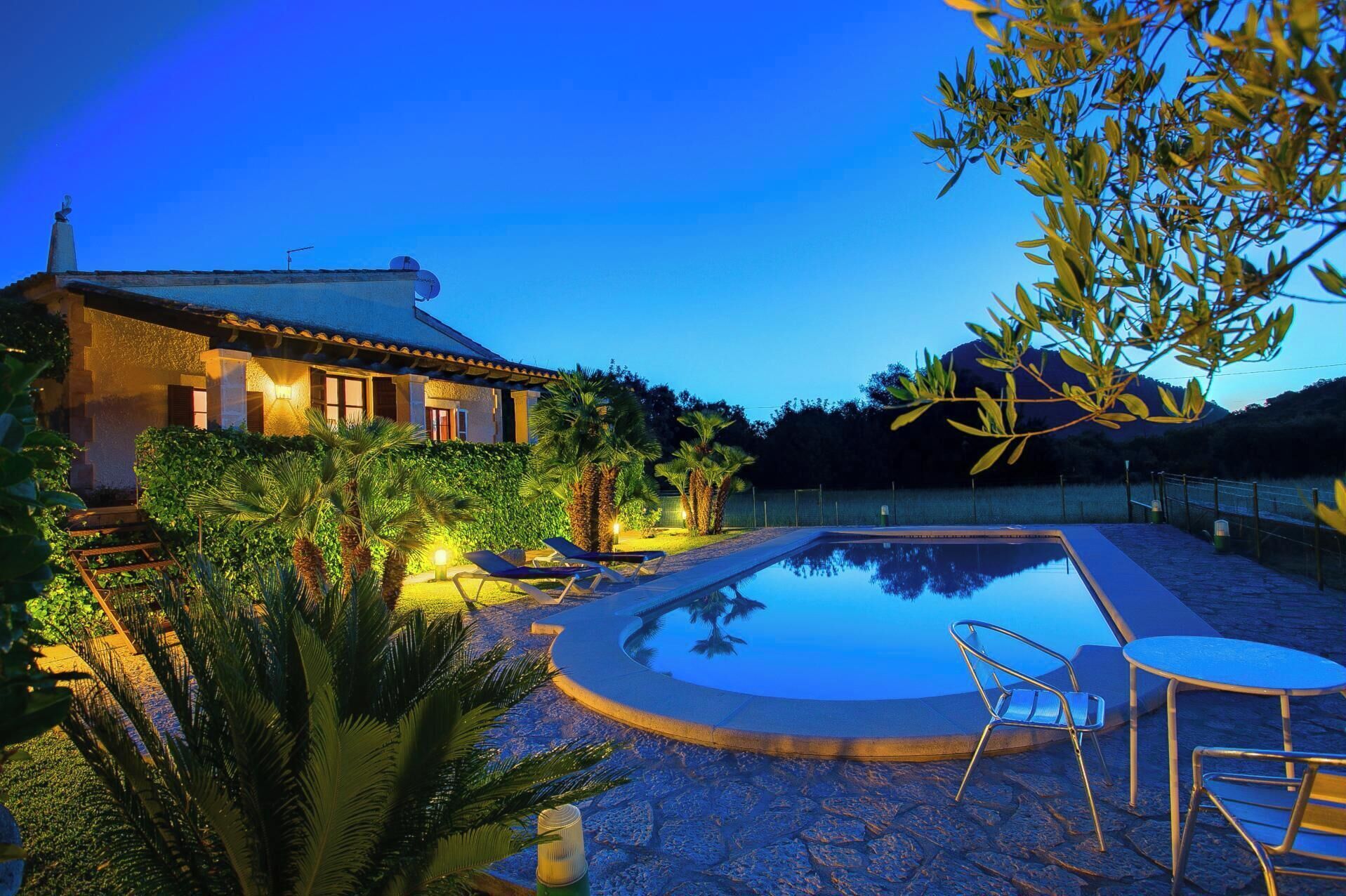 Una villa con piscina, rodeada de abundante vegetación y con montañas al fondo.