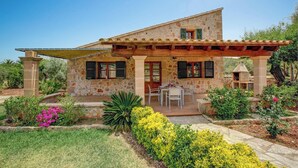 A stone house with a patio, outdoor seating, and a garden with various plants and flowers. - Attractive, Spacious Villa for Couples, A/C, Private Pool, Rural Views, Walking Distance to Pollenca (Pollença)