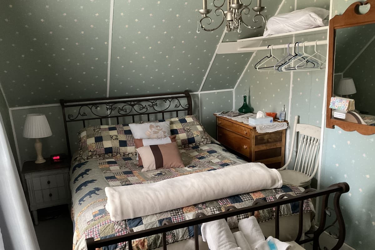 Un dormitorio con cama, mesita de noche, cómoda, espejo y lámpara colgante.