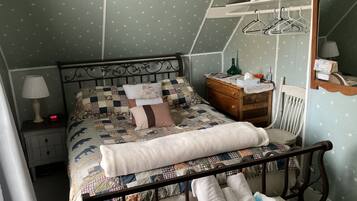 Un dormitorio con cama, mesita de noche, cómoda, espejo y lámpara colgante.