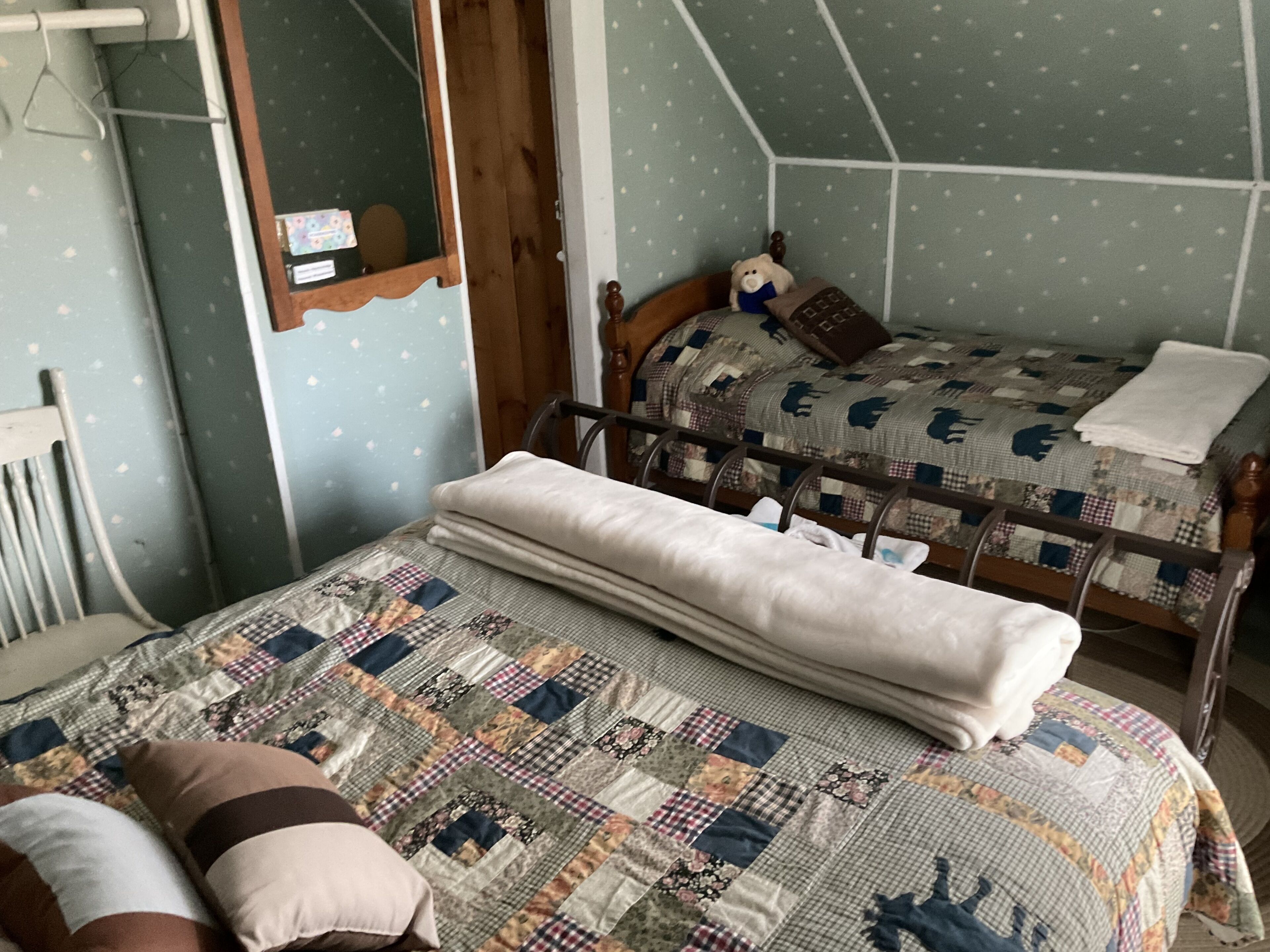 Un dormitorio con dos camas, cabeceros de madera, un espejo y una colcha acolchada.