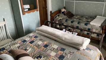 Un dormitorio con dos camas, cabeceros de madera, un espejo y una colcha acolchada.