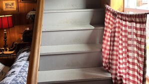 A staircase with a checkered curtain and a lamp on the left. - Seymour Lake Lodge (Morgan)