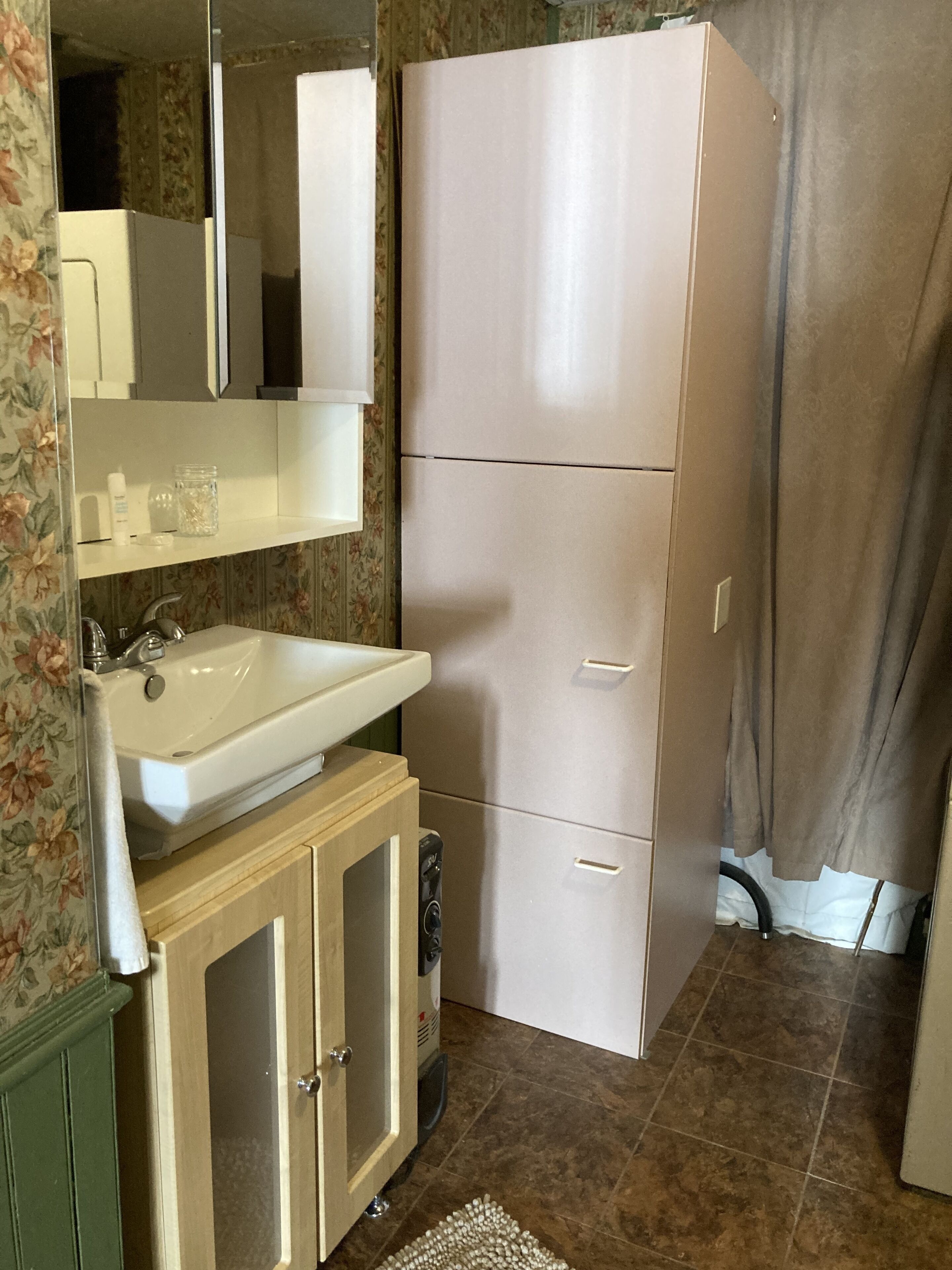 A compact kitchen with a sink, a mirror, a refrigerator, and a cabinet.