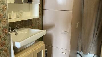 A compact kitchen with a sink, a mirror, a refrigerator, and a cabinet.