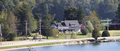 A lakeside house with a dock, surrounded by trees and a forested hill.