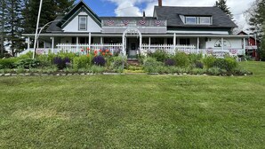 A two-story house with a porch, a flag, and a sign that reads "Vermont Country Inn." - Seymour Lake Lodge (Morgan)