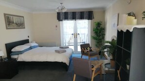 Une chambre d’hôtel avec un lit, une chaise, un bureau, une plante en pot et une armoire.