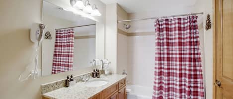 A bathroom with a sink, mirror, and shower curtain.