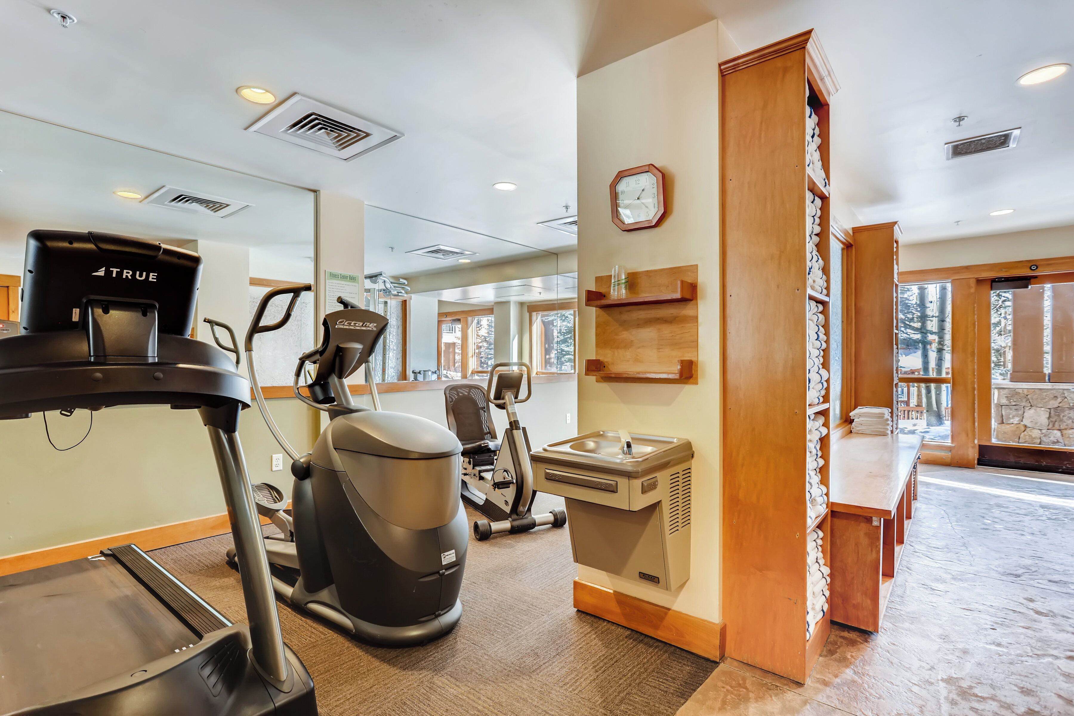A gym with treadmills, stationary bikes, and a water fountain.