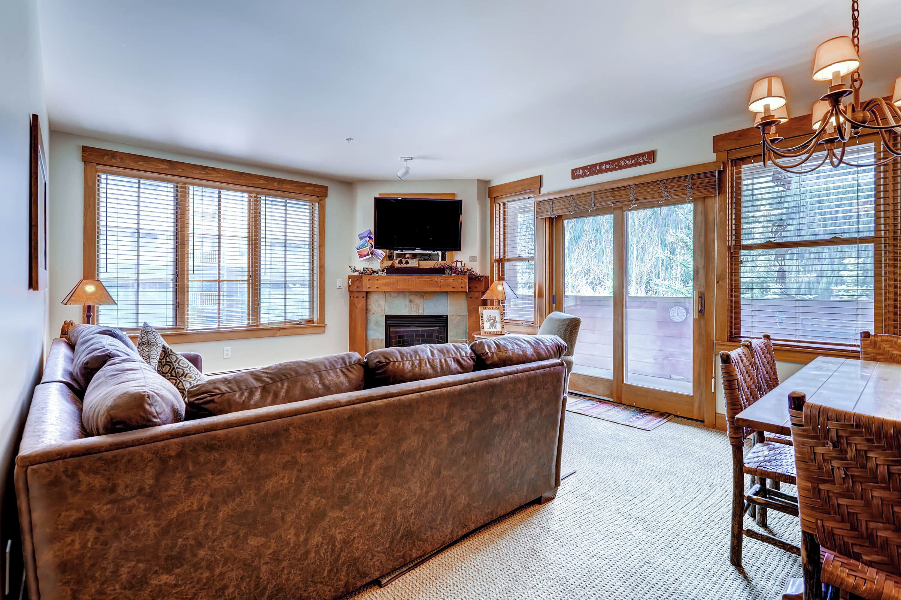 A spacious living room with a large sectional sofa, a fireplace, a television, and a dining area with a wooden table and chairs.