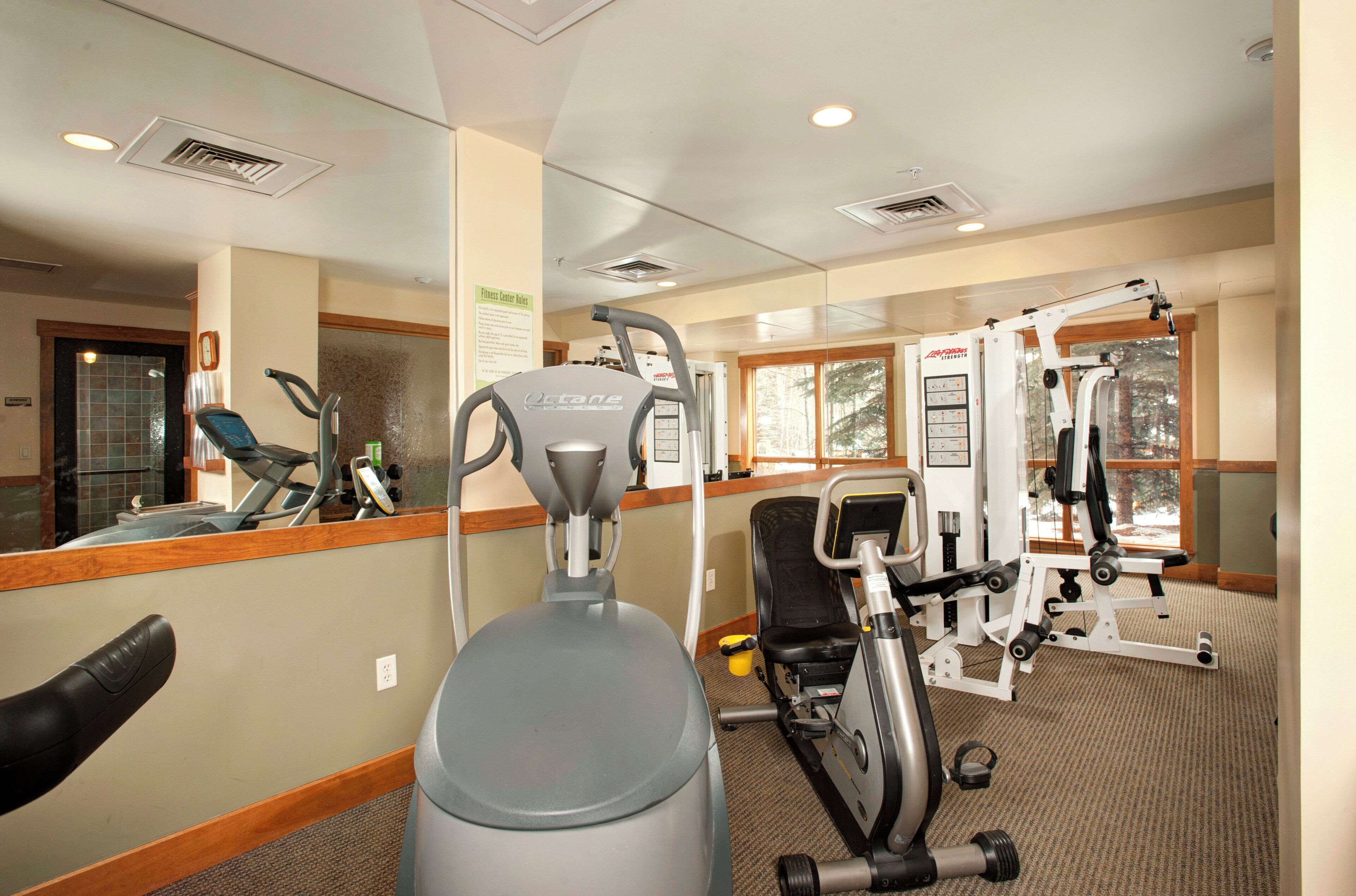 A gym with cardio equipment, weight machines, and a mirror.