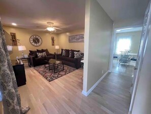 Relax in this stylish living room with a sofa, coffee table, and rug, surrounded by artwork and a large clock.