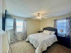 Cozy retreat with a single bed, ceiling fan, and flat-screen TV.