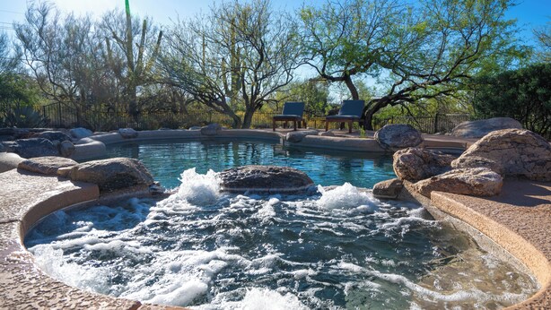 A hot spring area with a pool, rocks, and two lounge chairs. - Hacienda Riad: free pool heat, hot tub, views (Tucson)