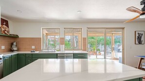 A kitchen with a large island, green cabinets, and a view through the glass doors. - Hacienda Riad: free pool heat, hot tub, views (Tucson)