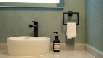 A bathroom with a white sink, a black soap dispenser, and a towel rack.