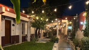 Un patio con sendero de baldosas, zona verde y luces colgantes.