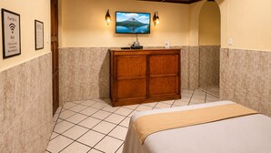 Una habitación de hotel con una cama, un armario de madera, un televisor y un suelo de baldosas.
