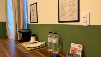 Et hotelværelse med en ind-/udtjekningsskærm, et skilt med 'Hello & Bienvenidos', et skilt med 'Gratis Wi-Fi', en fjernbetjening og et bakke med tallerken og kop.