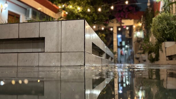 Un edificio moderno con una fuente de agua reflectante en primer plano.