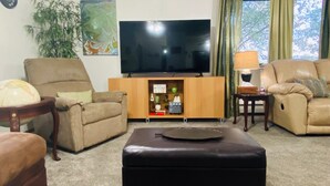 A living room with a flat-screen TV, two sofas, a coffee table, a lamp, and a bookshelf.