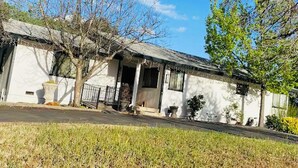 A white building with a porch, a small garden, and a clear blue sky.
