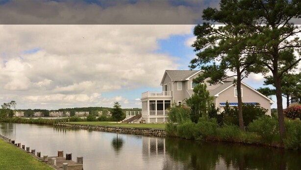 A lakeside property with a large house featuring a covered porch and a view of the lake. - Family Friendly Townhome in desired Stewards Watch Community- 5mins to the beach (Bethany Beach)