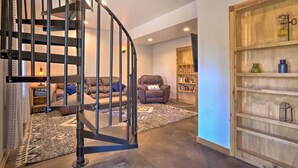 Uma sala de estar moderna com uma escada em espiral, um sofá, uma estante e um tapete decorativo.
