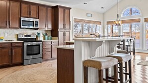Una cocina con armarios de madera, electrodomésticos de acero inoxidable y una isla grande con taburetes de bar.