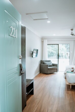Relax in this inviting room with a comfortable grey sofa and a white bed, featuring a simple and functional design.