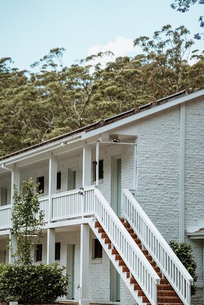Stunning two-story building with a central staircase and multiple windows, set amidst lush greenery.