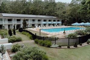 Relax by the pool surrounded by lush greenery and comfortable lounge chairs.