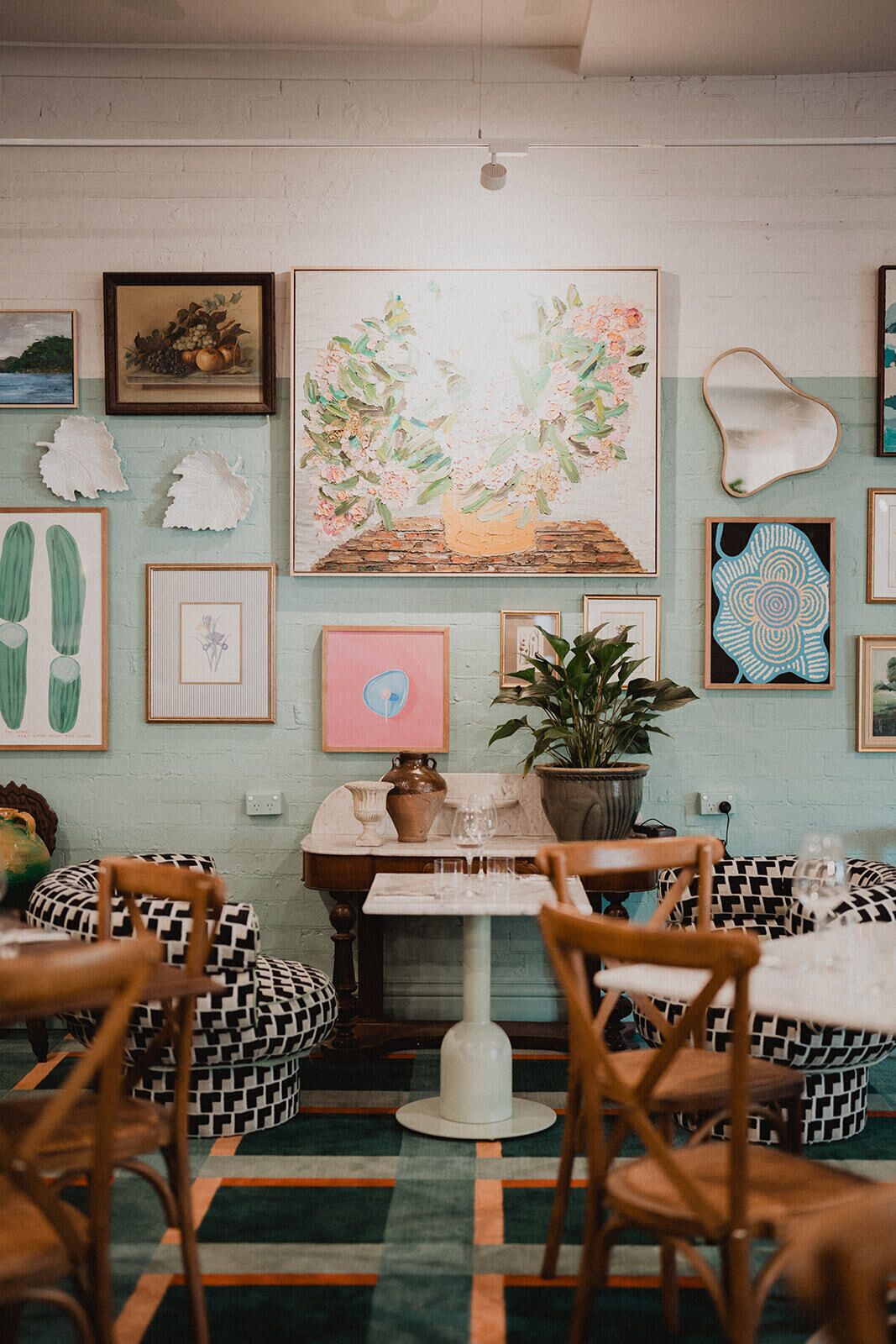 A cozy dining area with a table and chairs, surrounded by various framed artworks and decorative items.