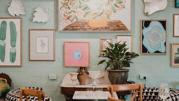 A cozy dining area with a table and chairs, surrounded by various framed artworks and decorative items.