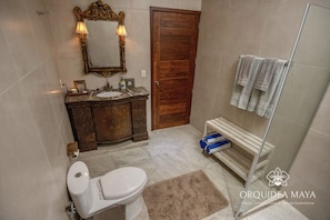 Ein Badezimmer mit Toilette, Waschbecken, Waschtisch, Spiegel und Duschbereich.