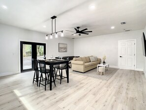 A modern living room with a dining area, a sofa, and a ceiling fan.