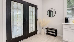 Ein modernes Interieur mit einer schwarzen Tür, einem runden Spiegel, einem kleinen Tisch und einem weißen Schrank.