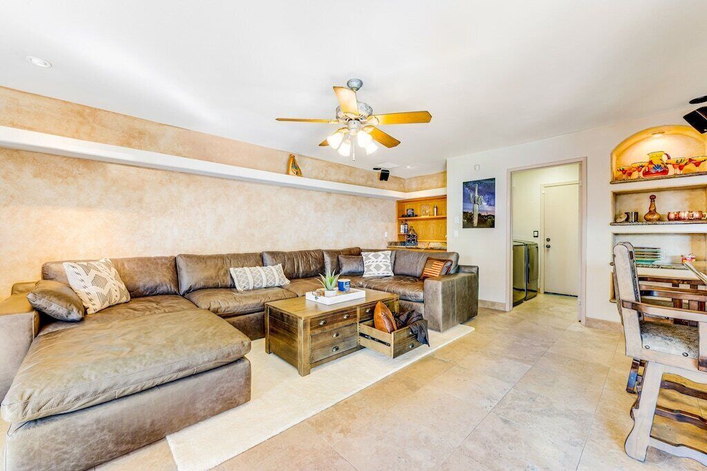A modern living room with a sectional sofa, wooden coffee table, and a ceiling fan.