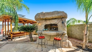 An outdoor bar area with stone seating and a stone fireplace. - Backyard Oasis Ideal for Spring/Summer! Pool, Misters, Bluetooth Speakers + more (Mesa)