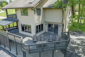 A two-story house with a covered deck, large windows, and a sliding glass door.