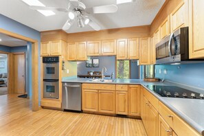 A modern kitchen with wooden cabinets, stainless steel appliances, and a large island. - Creekside 4BR w/ Firepit - 5 Min to Sports Park - 10 Min to Downtown Asheville (Candler)