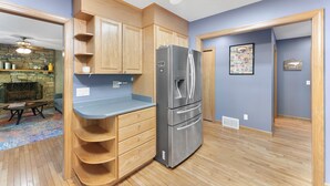 Una cocina compacta con armarios de madera, un refrigerador de acero inoxidable y una chimenea de piedra.