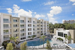 Um hotel moderno com vários andares, piscina central e áreas de estar ao ar livre.