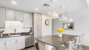 Una cocina moderna con armarios blancos, electrodomésticos de acero inoxidable y una isla central con sillas.