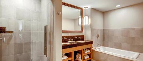 A modern bathroom with a walk-in shower, a large mirror, and a bathtub.
