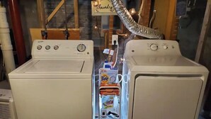 Two white front-loading washing machines side by side with a transparent detergent dispenser in between.