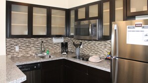 Una cocina moderna con armarios oscuros, un refrigerador de acero inoxidable, un microondas y un lavavajillas.