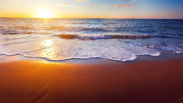 Una playa con olas al atardecer.