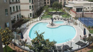 Una piscina con sillas de descanso y un pequeño jardín.
